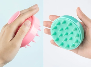 Detail of pink and green silicone scalp massager brush with ergonomic grip and soft bristles