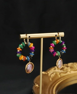 Detail of colorful beaded hoop earrings with hanging pinkish-purple irregular pearls
