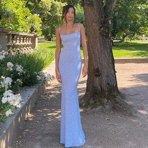 Vue extérieure d'une robe longue fleurie bleue ajustée avec dos nu et bretelles