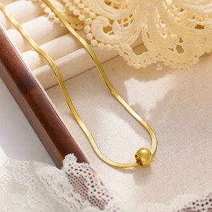 Detailed shot of golden snake chain necklace with round bead pendant in a jewelry box