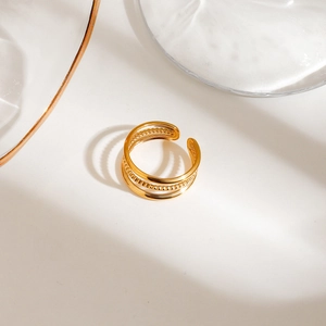 Detail of gold stacked open rings with smooth bands and beaded textures on a white surface