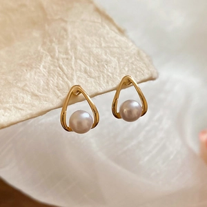 Macro detail of French vintage waterdrop gold pearl earrings on textured paper