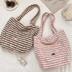 Detail view of pink and brown striped plush tote bags with metal logo on soft fabric
