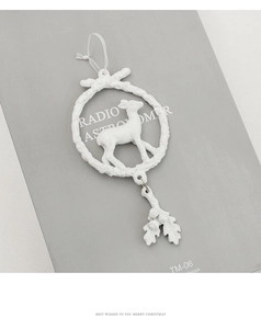 Macro detail of a white resin reindeer wreath ornament with delicate oak leaf pendants