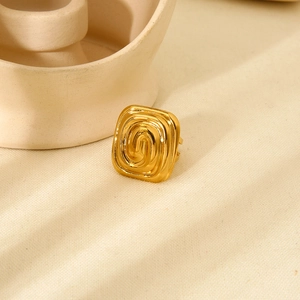 18K gold plated stainless steel square ring with swirl texture on a beige fabric surface