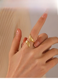 Detail of an adjustable 18K gold plated leaf ring on a finger with soft lighting