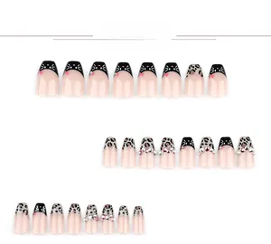 Detail of leopard print press-on nails with black cat designs and pink rhinestones