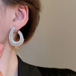Close-up of a model wearing sparkling zircon C-shaped silver earrings with mixed cuts