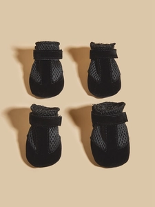 Detail view of four breathable black mesh dog shoes with adjustable velcro straps