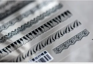 Détail d'autocollants pour ongles en dentelle noire vintage avec bordures florales et étiquette