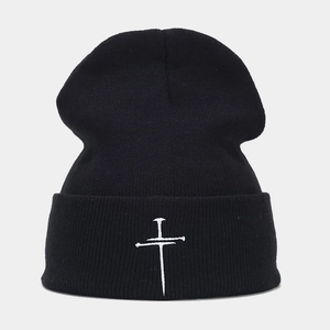Detailed close-up of a black ribbed knit beanie with white cross embroidery