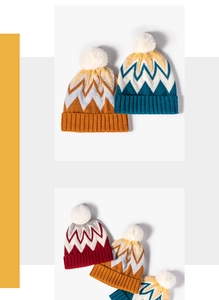 Detail of winter knit hat with white faux fur pom-pom and zigzag jacquard pattern