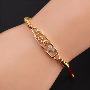 Vista macro bracciale Love placcato oro con cordino rosso e zirconi scintillanti