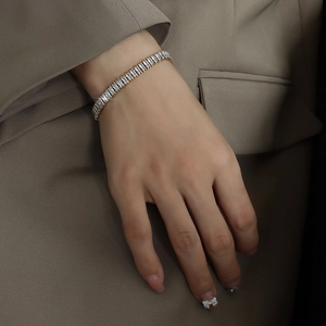 Dettaglio del bracciale in zircone dorato con cristalli rettangolari indossato al polso