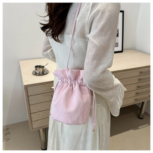 Rear view of a pink drawstring bucket bag worn by a model in a minimalist home setting