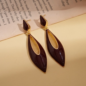 Macro detail of vintage teardrop earrings with burgundy enamel and gold frames