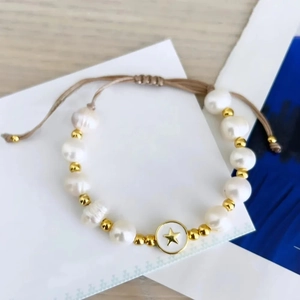 Detail of adjustable pearl bracelet featuring enamel star charm and woven cord texture
