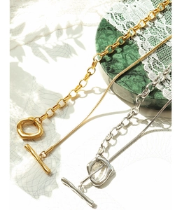 Detail of OT buckle adjustable gold and silver chain necklaces on marble background