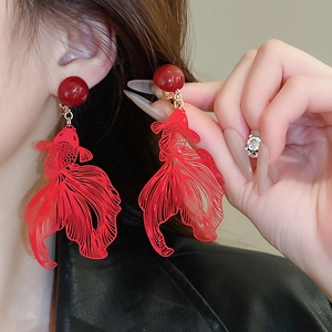 Close-up of a model wearing red hollow goldfish drop earrings with intricate metal lines