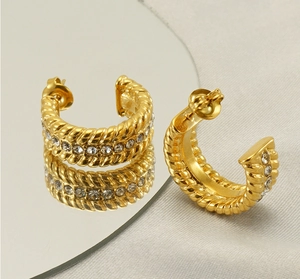 Detail of gold U-shaped twisted earrings with double-row zircon pavé on a mirror surface