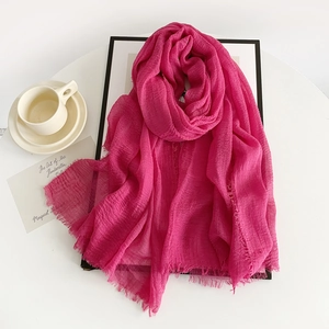 Detail of rose red cotton linen scarf with frayed edges and elegant fabric texture