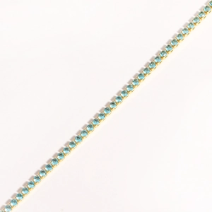 Close-up of gold-plated tennis bracelet with single row of claw-set blue round zircons