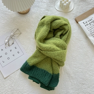 Flat lay of soft knit green patchwork scarf with cozy aesthetic home decor accents