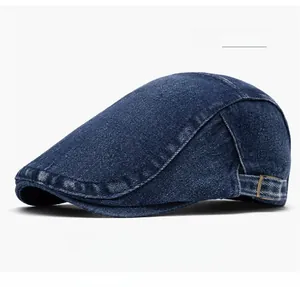Detail of dark blue denim beret showing white stitching and adjustable metal buckle strap