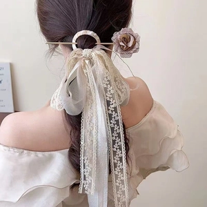 Detail of vintage French hair pin featuring a fabric rose, pearls, and long lace ribbons