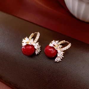Detailed macro of 18k gold-plated earrings featuring red beads and micro-set zircon floral design