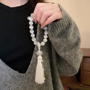 Detail of opal cat eye lotus flower bracelet with elegant white silk tassel on wrist