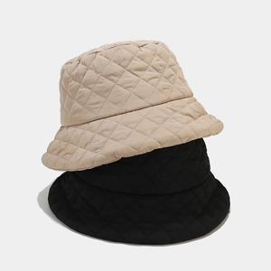 Detail of beige and black quilted winter bucket hats with diamond stitching pattern