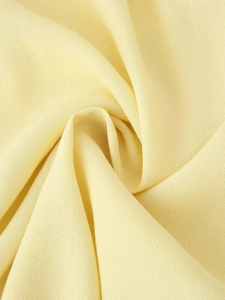 Macro shot of light yellow tiered fabric texture and stitching of the layered blouse