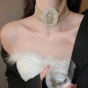 Detail of a gold wide rhinestone choker featuring an oval centerpiece on a model