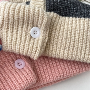 Detailed view of the ribbed knit texture and button closure on balaclava hats in various colors