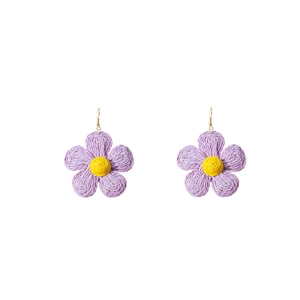 Detail of handmade raffia flower earrings in purple and yellow woven texture