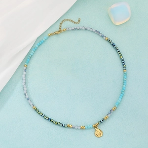 Detail view of blue and gold beaded necklace featuring a metallic ladybug pendant