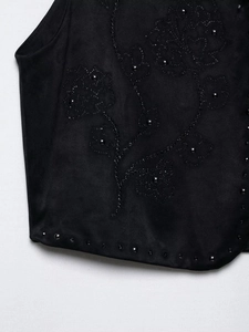 Dettaglio del gilet in velluto nero con ricami floreali di perline e paillettes lucide