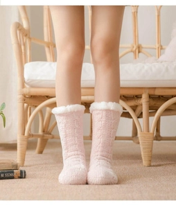 Pink cable knit winter slipper socks with white faux fur trim shown in a cozy home setting