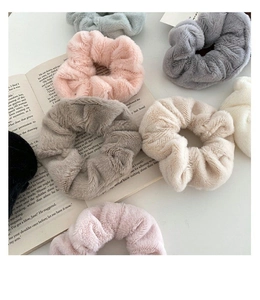 Flat lay of soft plush faux rabbit fur scrunchies in various pastel colors on a book