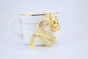 Gros plan d'un porte-clés dragon doré avec des strass colorés et une perle