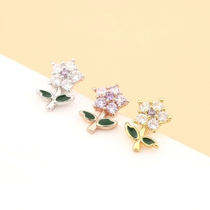 Vue macro de boucles d'oreilles fleur colorées en finition or et argent avec zircons