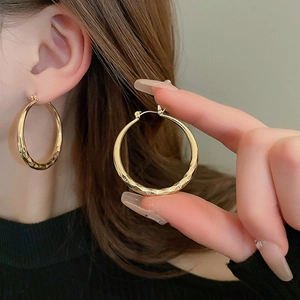 Macro detail of gold geometric hoop earrings showing faceted texture and metallic shine