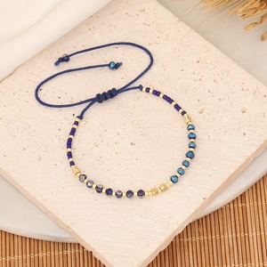 Detail of blue crystal beaded bracelet with adjustable woven cord on textured stone