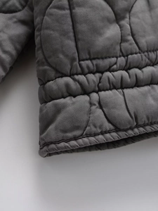 Detail shot of grey quilted jacket with twill texture and elastic ribbed cuffs for warmth