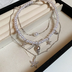 Close-up of layered necklace set with starfish, seashell pendants and white pearls