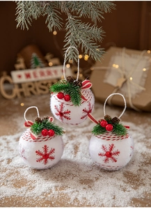 Detailed view of plush white Christmas ball with red snowflakes and pine cone accents