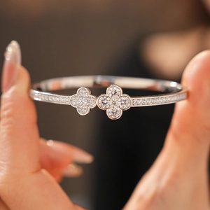 Macro shot of silver clover bracelet with inlaid zircons held in hand with soft bokeh