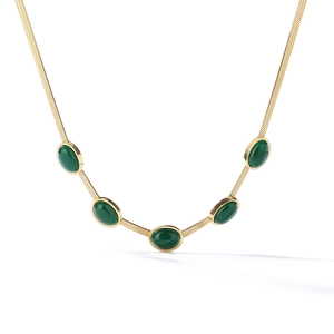 Detail of gold snake chain necklace featuring five oval emerald green gemstone charms