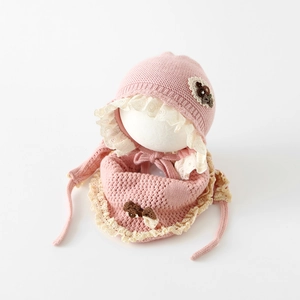Détail d'un ensemble bonnet et écharpe en tricot rose avec dentelle et fleurs
